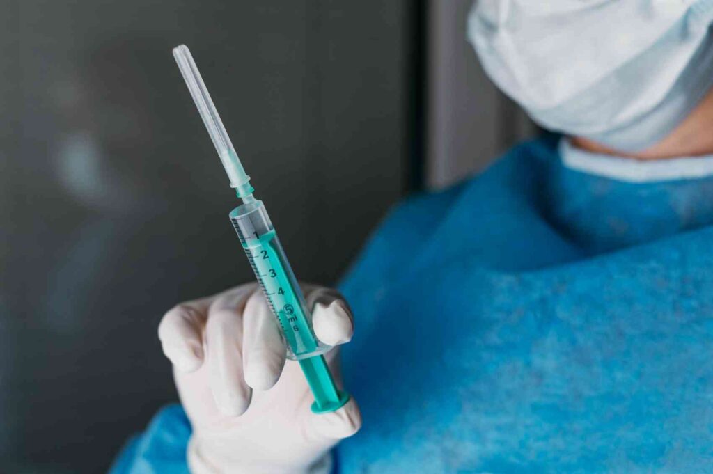 doctor-holding-vaccine-bottle-while-wearing-protective-equipment
